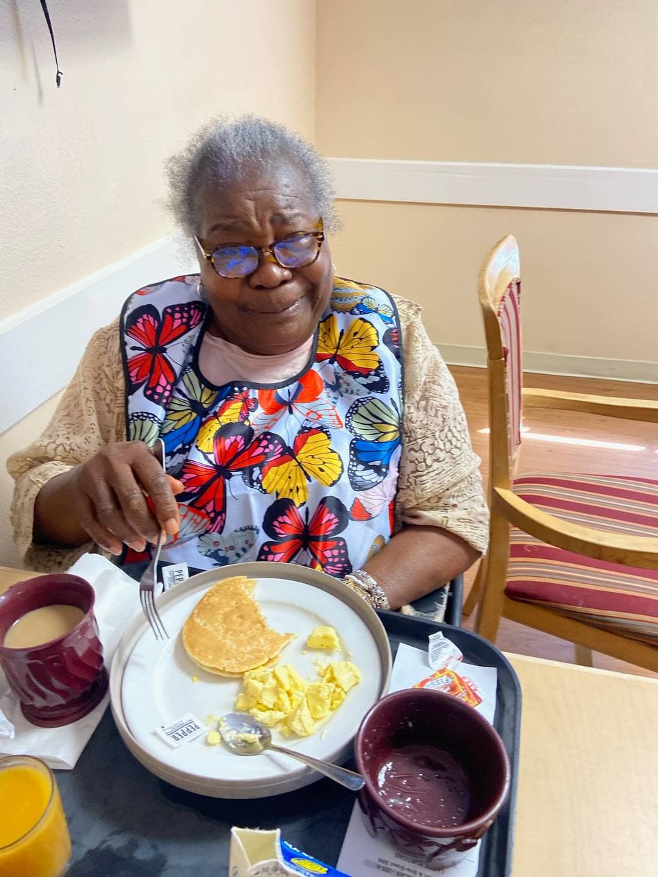 Christianne smiling softly over breakfast with eggs, toast, and juice.