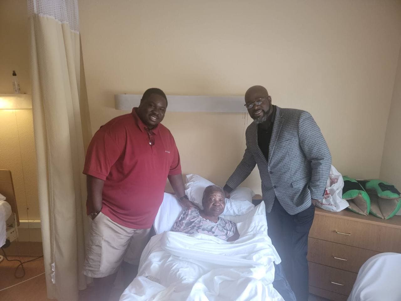Christianne in a hospital bed surrounded by two loved ones.