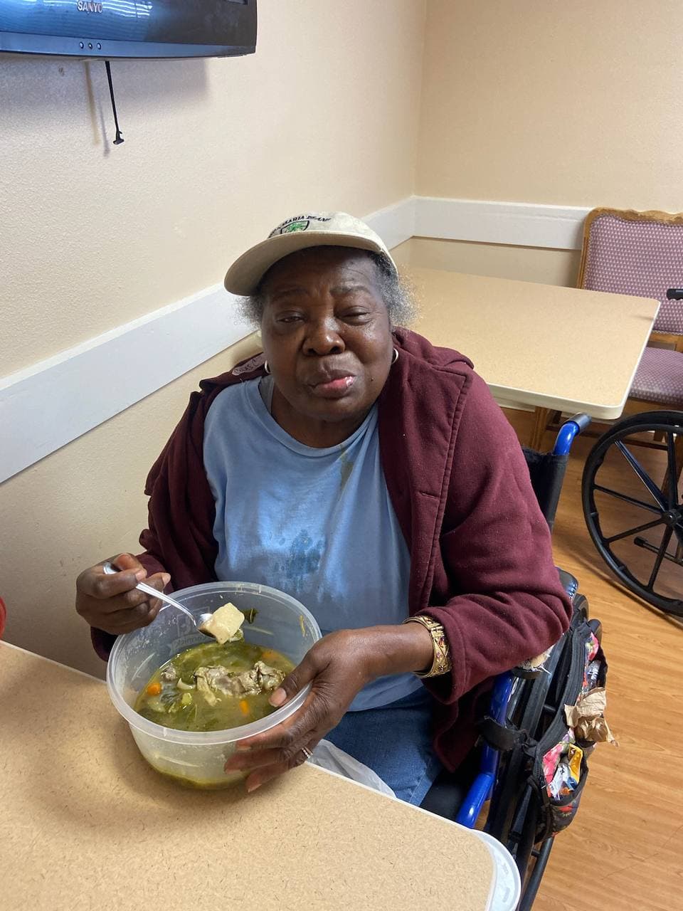 Christianne enjoying a meal while seated in a wheelchair.