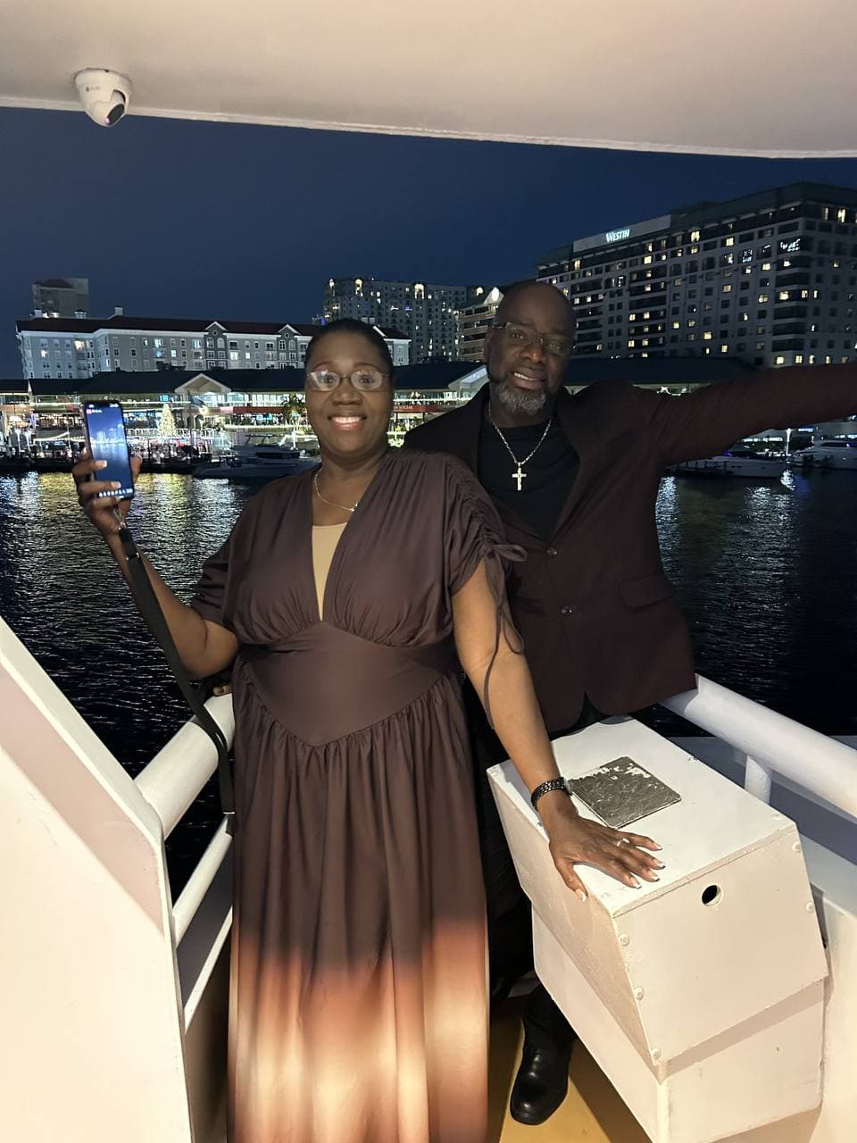 Two loved ones smiling together during a nighttime outing by the water.