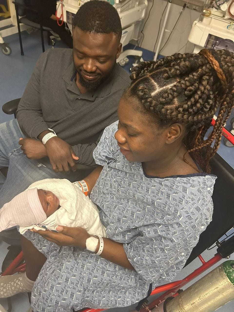 A family holding a newborn together in the hospital.